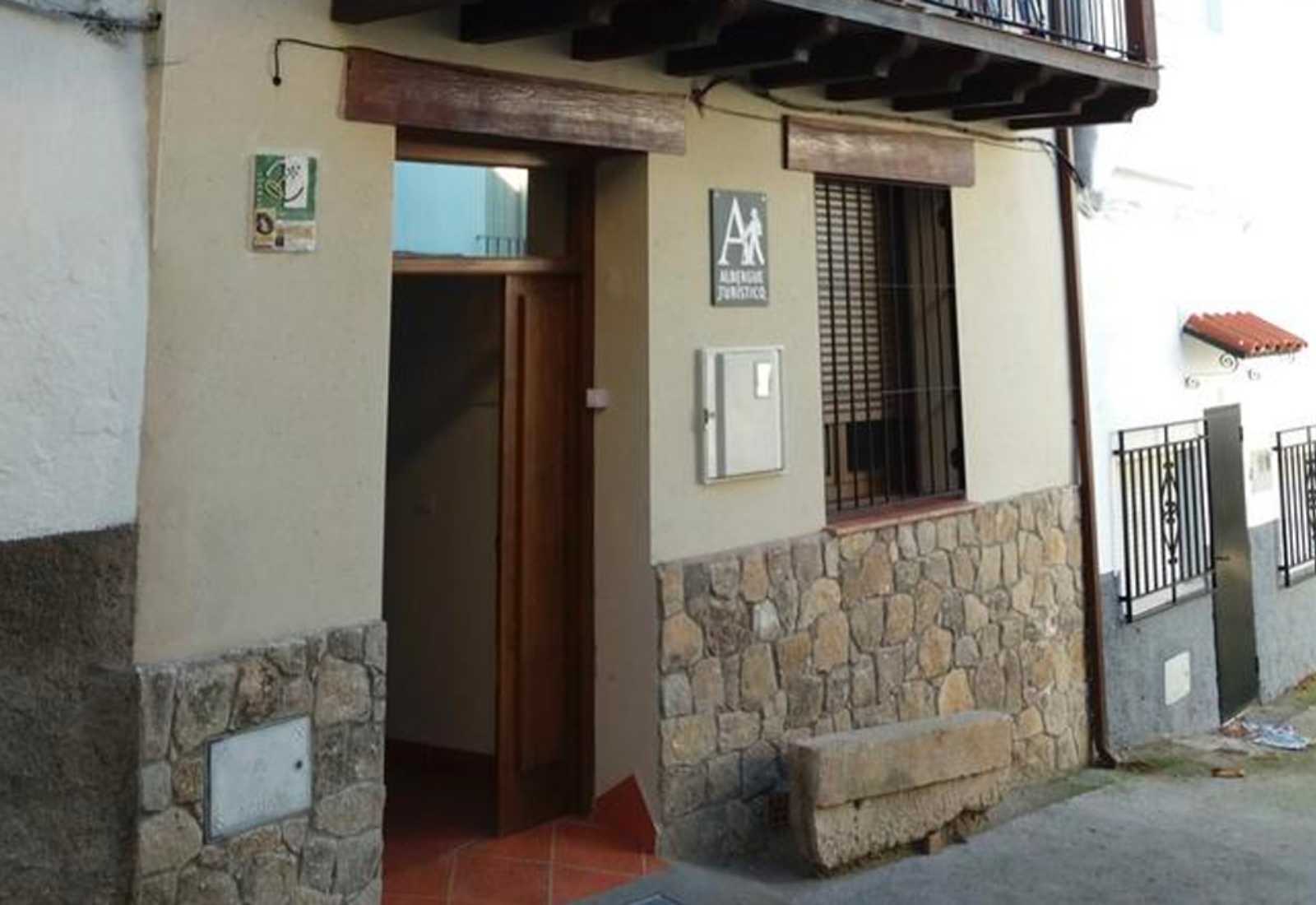 Doorway of a tourist hostel with an open door and stone base in Aldeanueva del Camino, stage towards La Calzada de Béjar