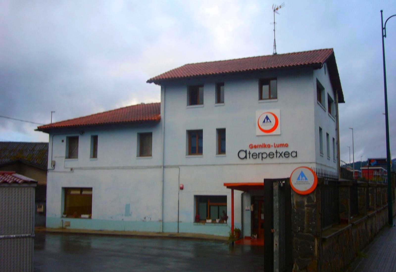 Auberge de pèlerins à façade blanche et toit rouge avec son enseigne par temps nuageux sur l'étape de Gernika-Lumo à Lezama du Chemin du Nord.