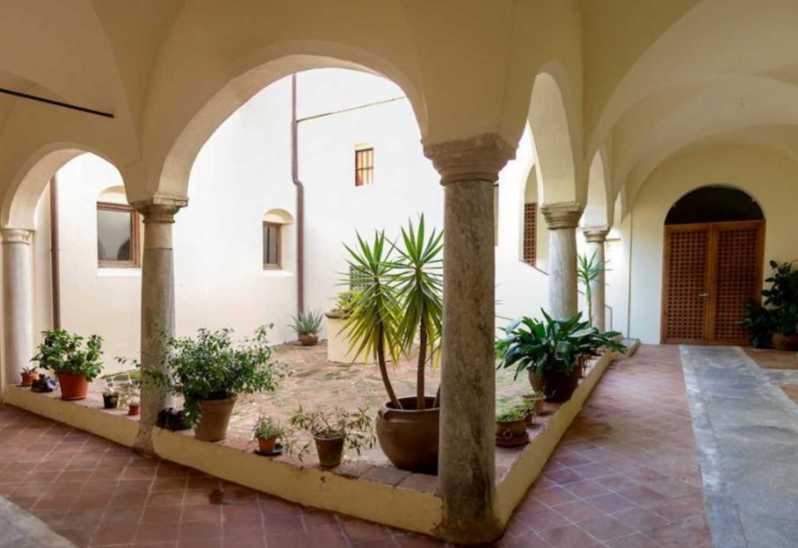Cloistered patio with stone columns, arches and potted plants in a hostel on the stage From Zafra to Villafranca de los Barros.