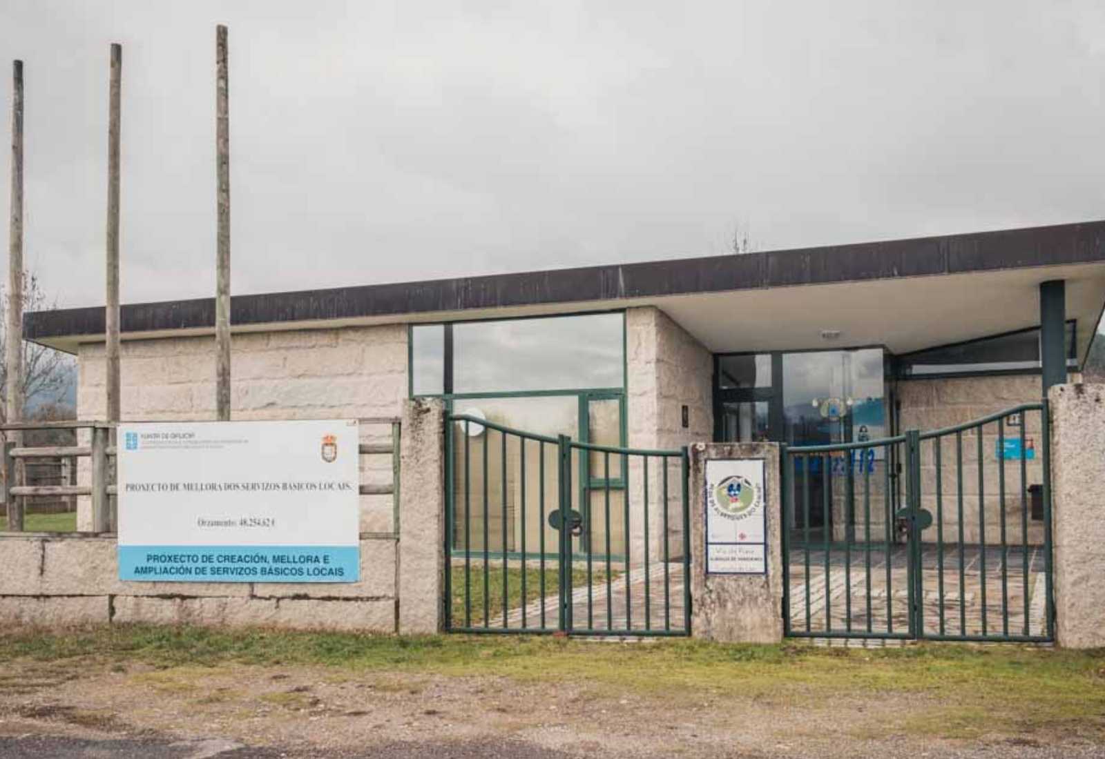 Ein steinernes Gemeindegebäude mit grünem Tor und Infotafel in Laza, Beginn der Etappe von Laza nach Xunqueira de Ambía.