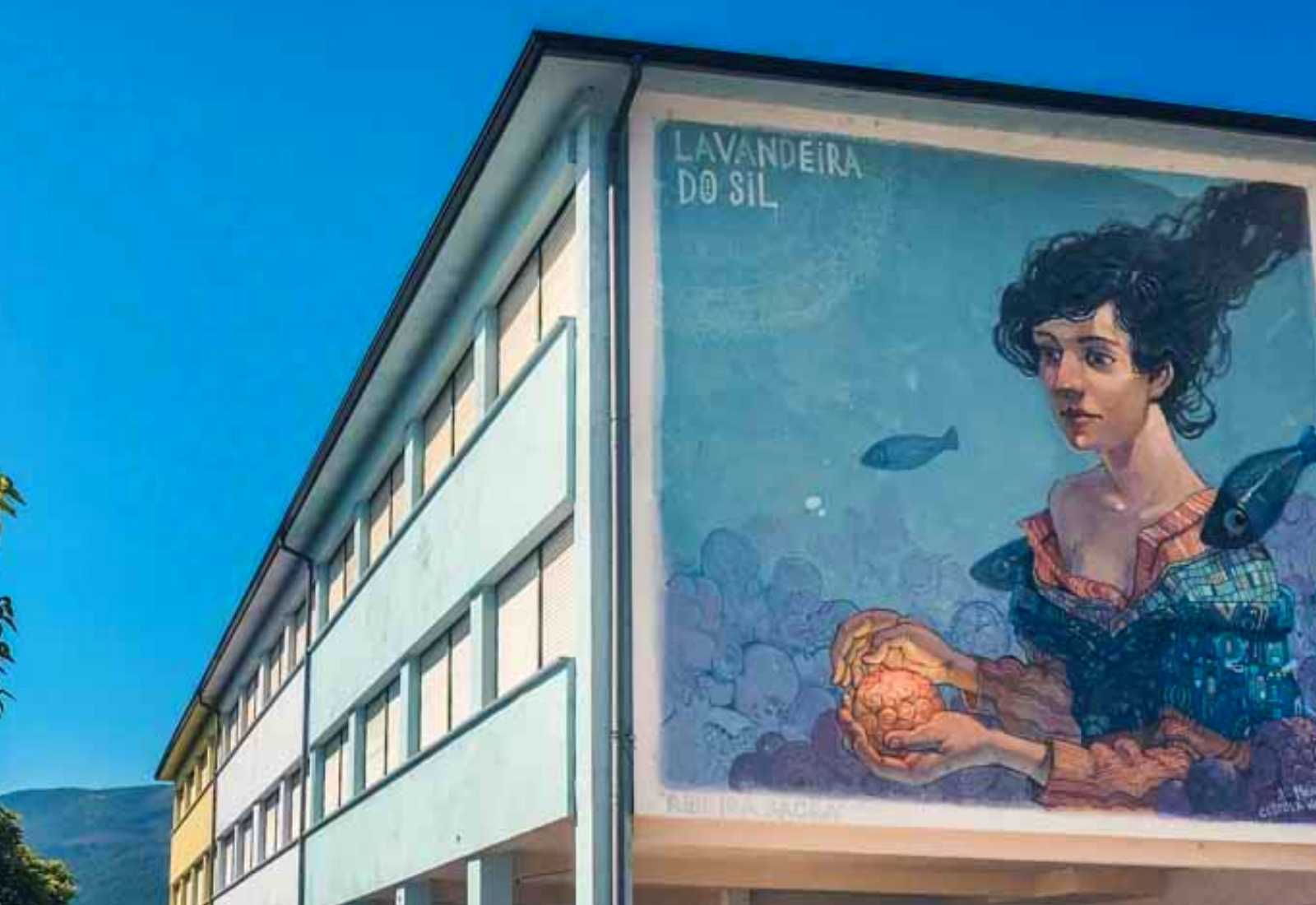 Albergue municipal con un gran mural de una mujer y peces en la fachada en la etapa de Quiroga a Monforte de Lemos.