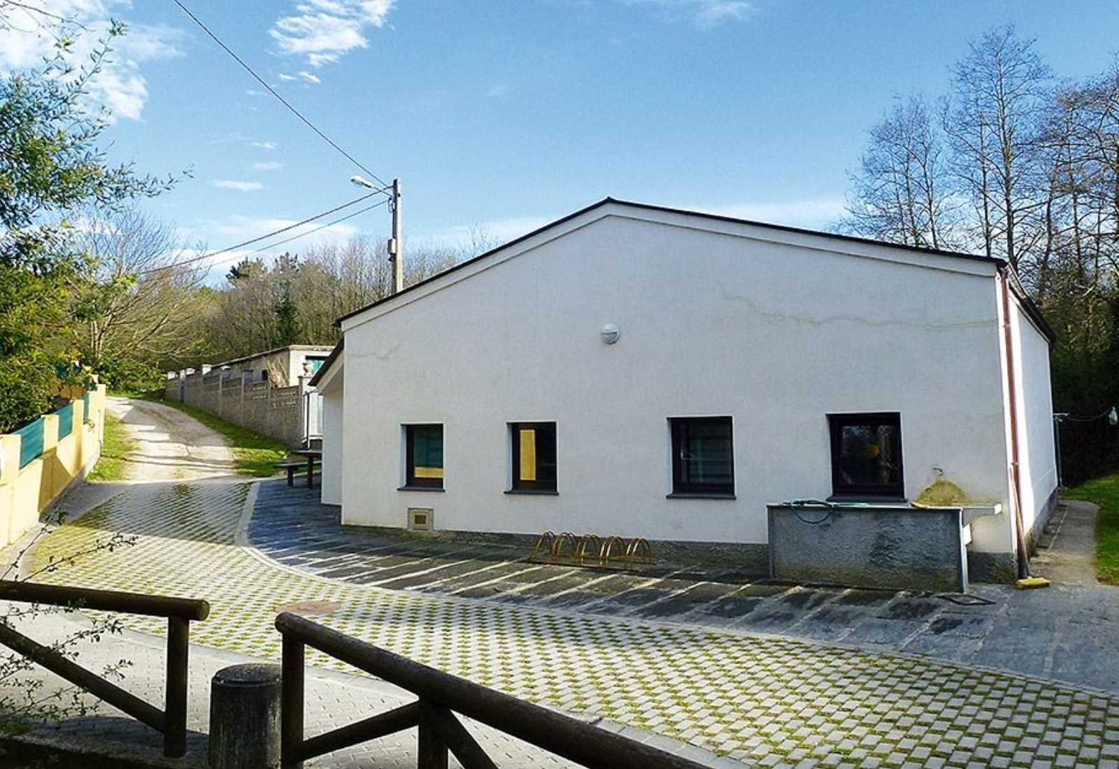 Auberge de pèlerins blanche toute simple avec avant-cour pavée et chemin rural sur l'étape de La Caridad à Ribadeo du Chemin du Nord.