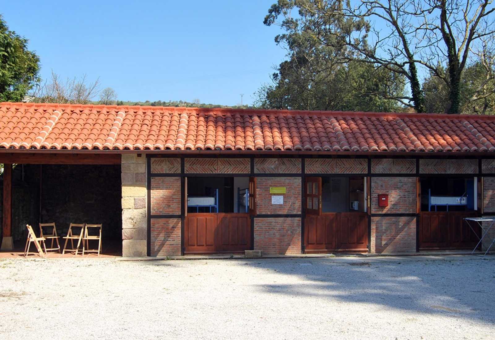 Gîte de pèlerins de plain-pied au toit rouge avec des chaises dans la cour sur l'étape de Santander à Santillana del Mar du Chemin du Nord.