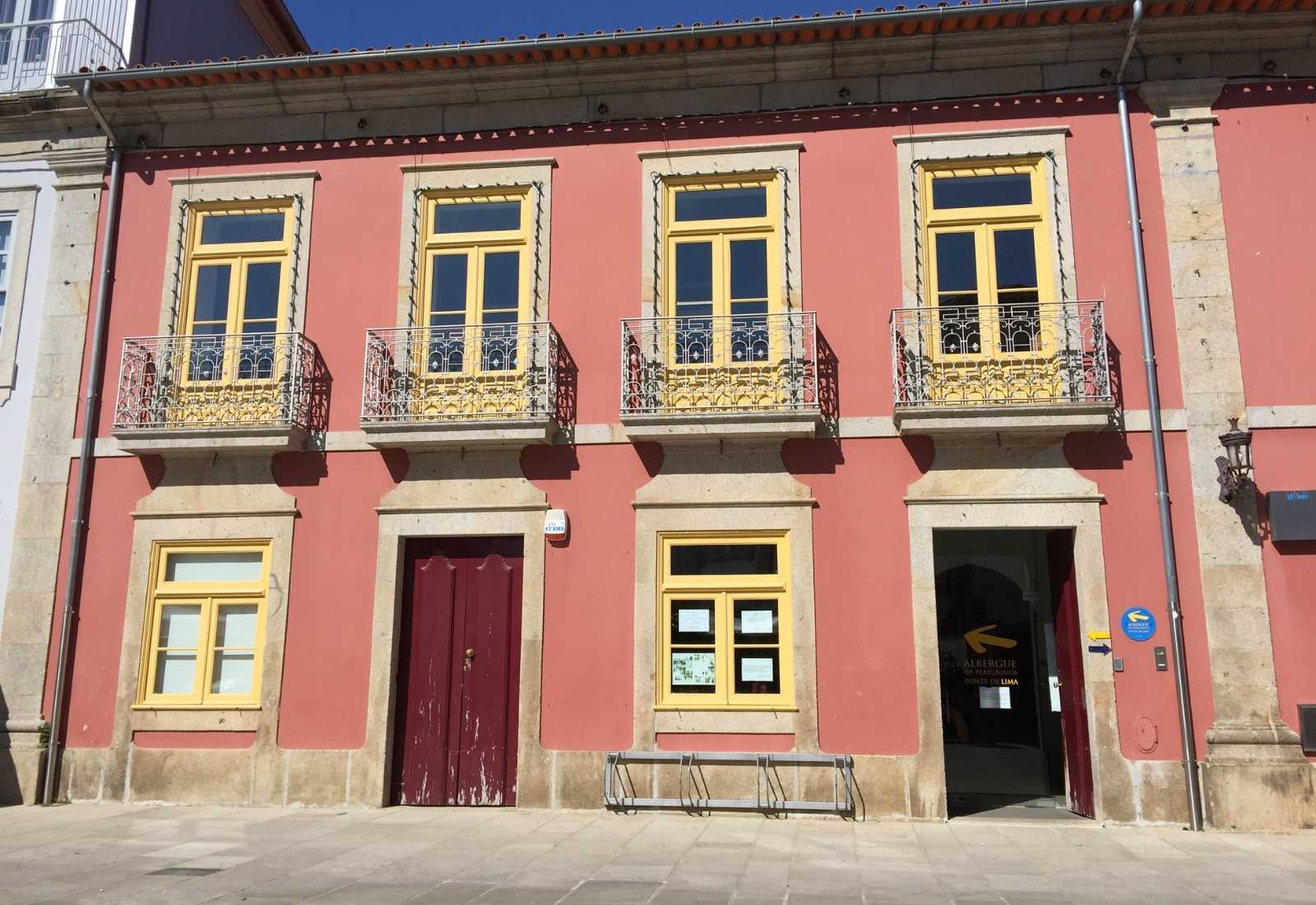 Fachada rosa do albergue de Ponte de Lima com placa e seta do Caminho na etapa de Barcelos a Ponte de Lima do Caminho Português