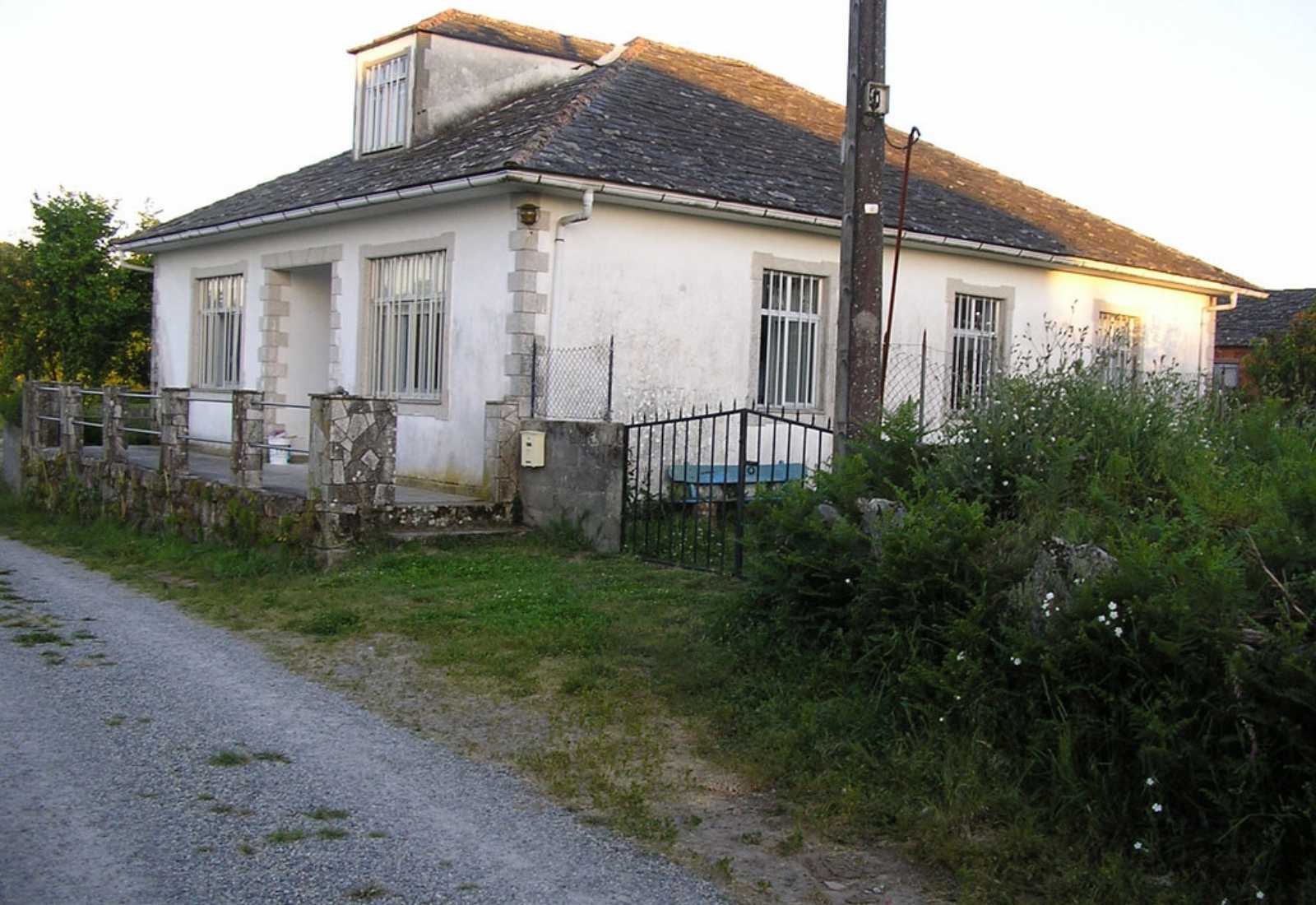 Modeste auberge de pèlerins, bâtiment blanc au bord d'un chemin de gravier à Miraz, étape De Baamonde à Miraz du Chemin du Nord.