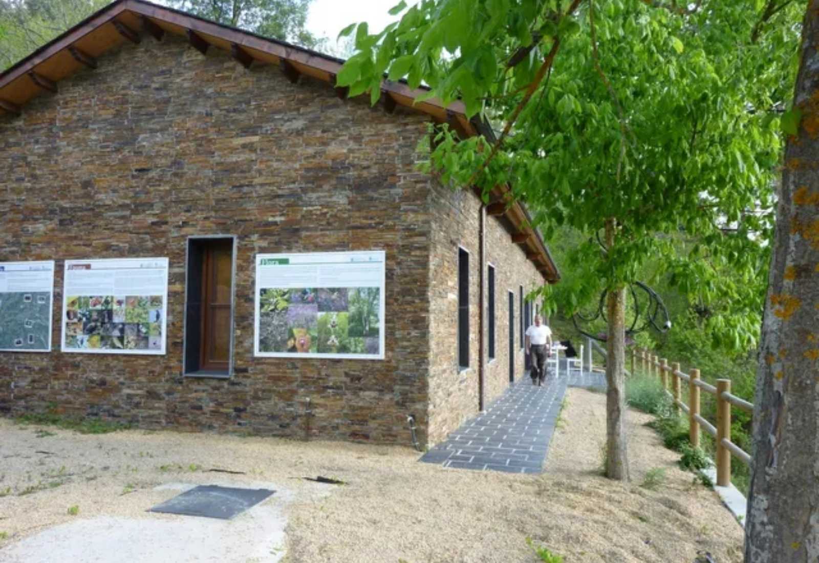 Albergue de piedra con paneles informativos y un sendero de losas en la etapa De Barco de Valdeorras a A Rúa de Valdeorras.