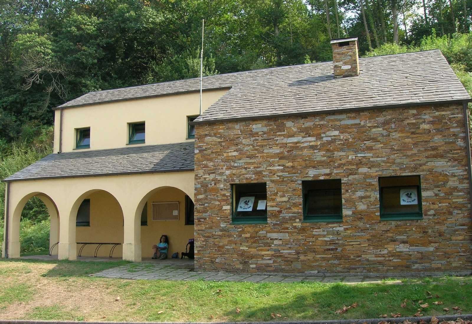 Auberge de la Xunta à Lourenzá avec un porche à arcades et une pèlerine au repos, étape vers Abadín du Chemin du Nord