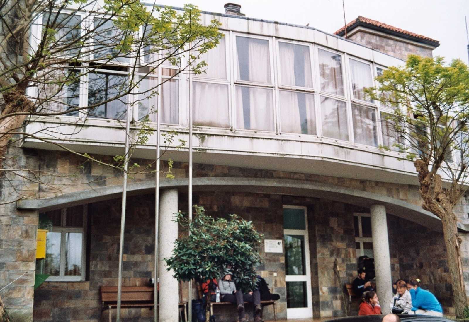 Peregrinos a descansar com as mochilas diante de um albergue público na etapa de Ferreira a Melide do Caminho Primitivo