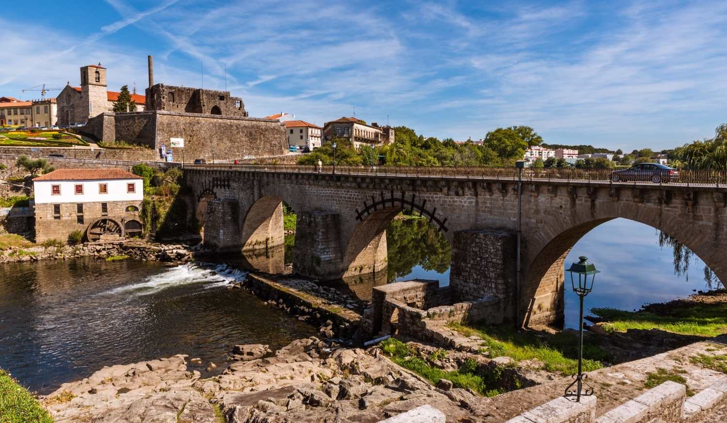 Barcelos e a sua ponte medieval sobre o rio com a torre da igreja e um moinho na etapa de Barcelos a Ponte de Lima do Caminho Português