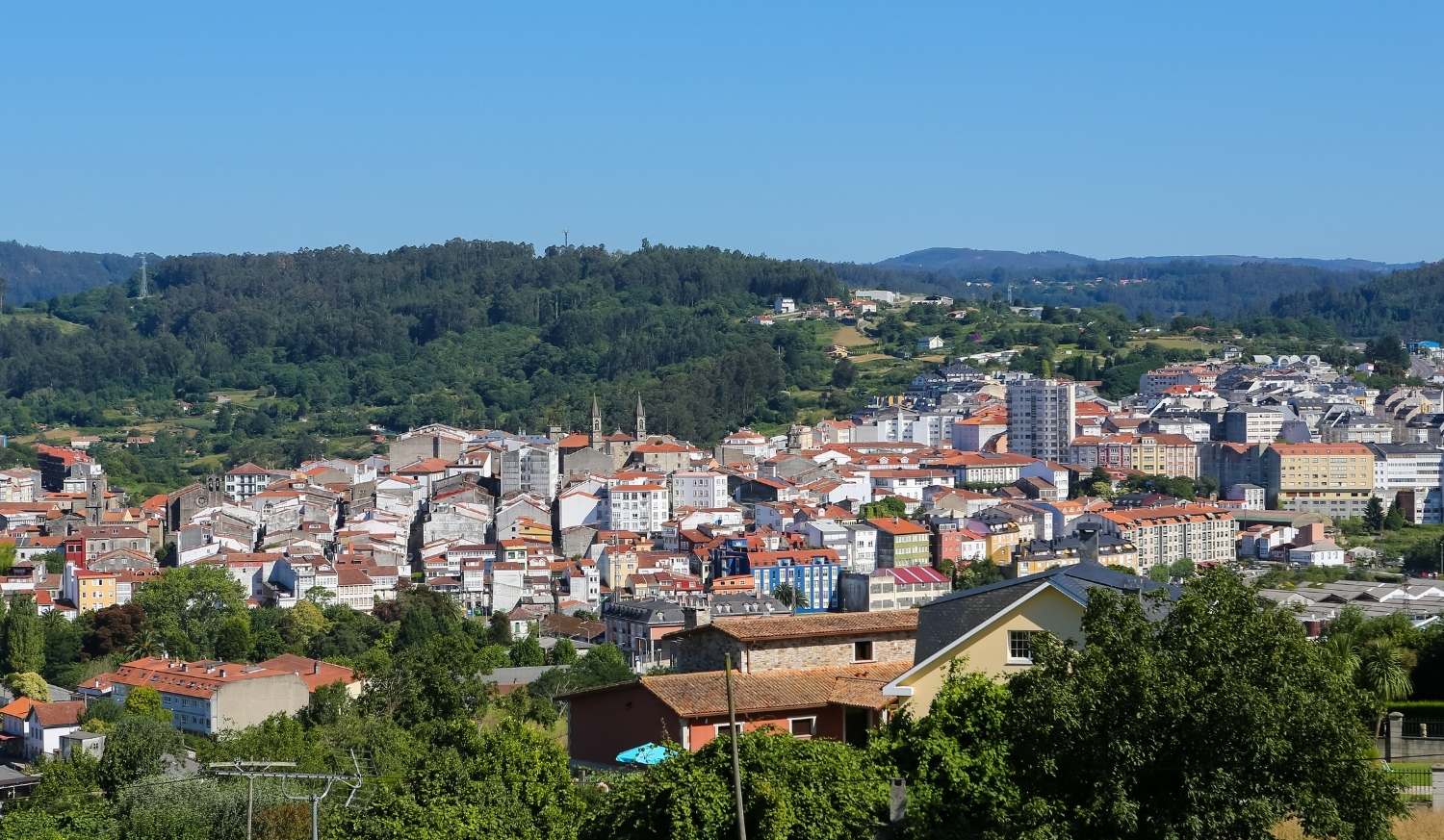 Panorama von Betanzos mit Kirchtürmen und bunten Häusern zwischen grünen Hügeln, Etappe nach Hospital de Bruma