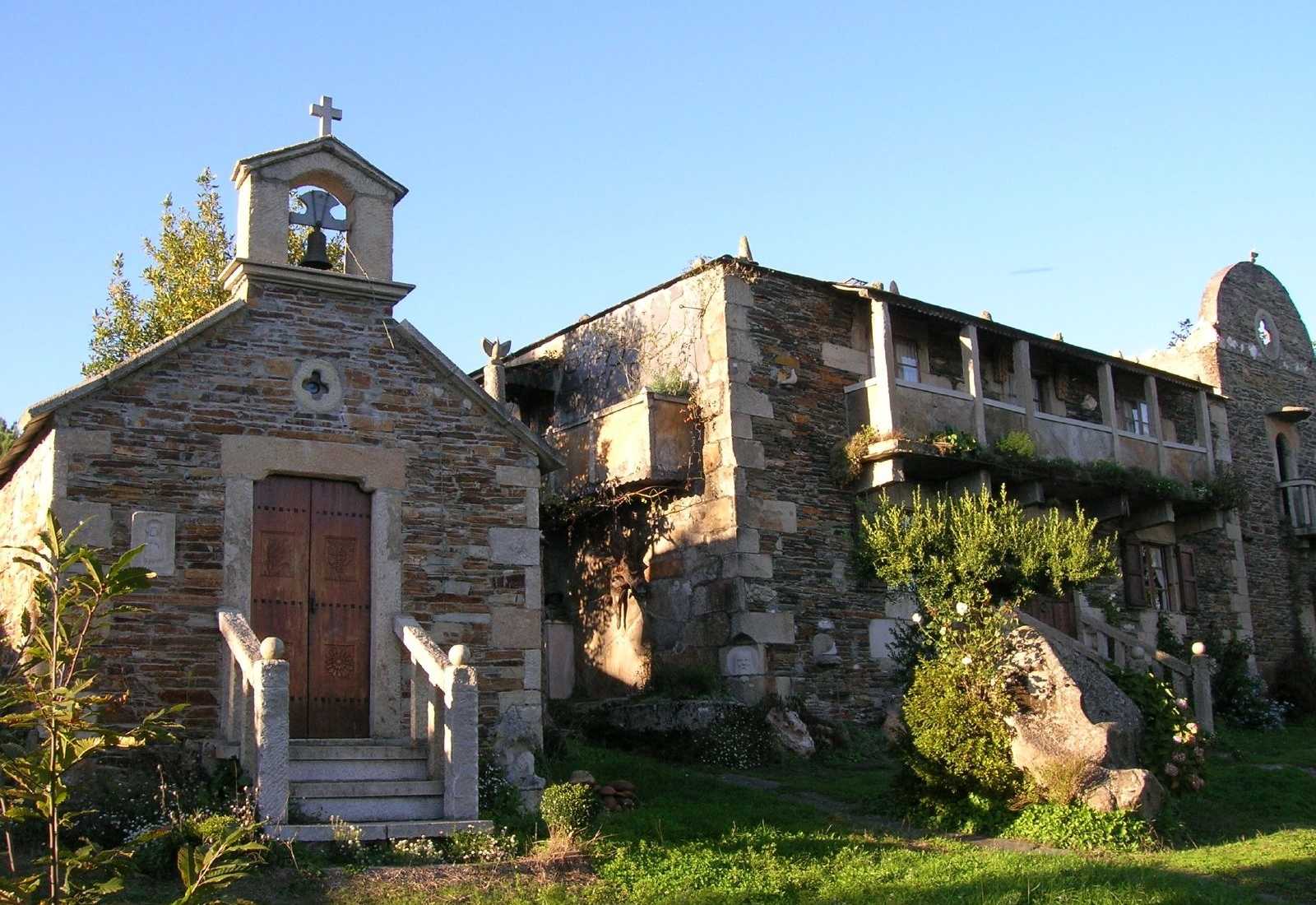 Kleine Steinkapelle mit Glockengiebel neben einem rustikalen Steinhaus in Baamonde, Etappe Von Baamonde nach Miraz des Küstenwegs.