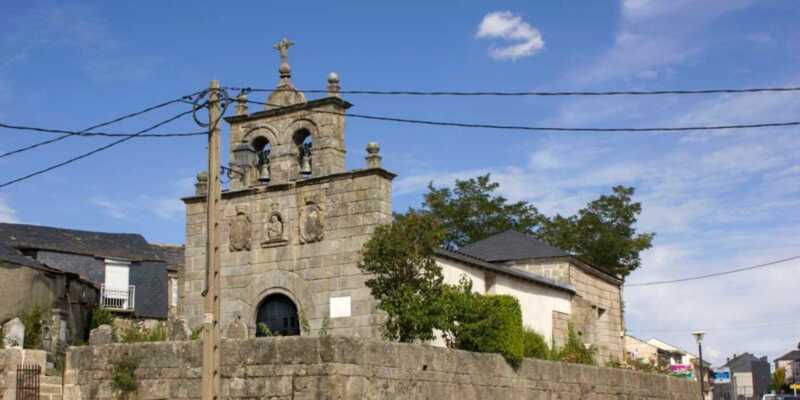 Granitkirche mit Glockengiebel und Kreuz in einem galicischen Dorf auf der Etappe Von A Gudiña nach Laza.