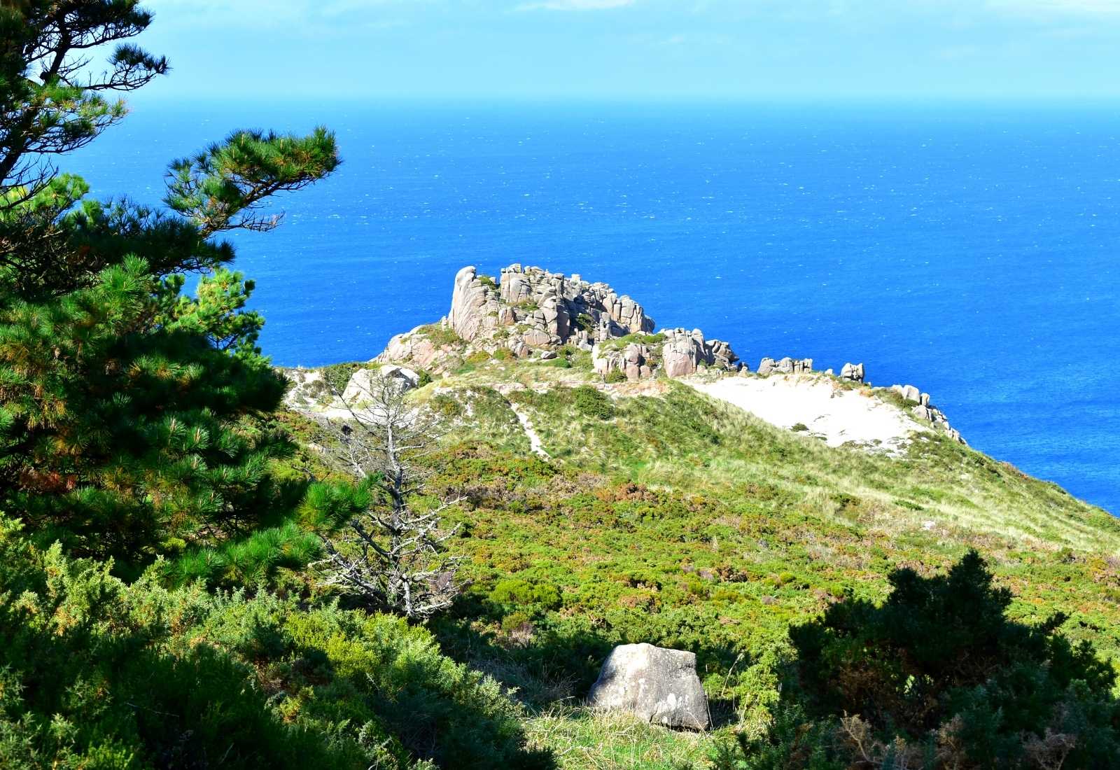 Ladera verde y peñascos sobre el océano azul intenso en la etapa de Arou a Camariñas del Camino dos Faros