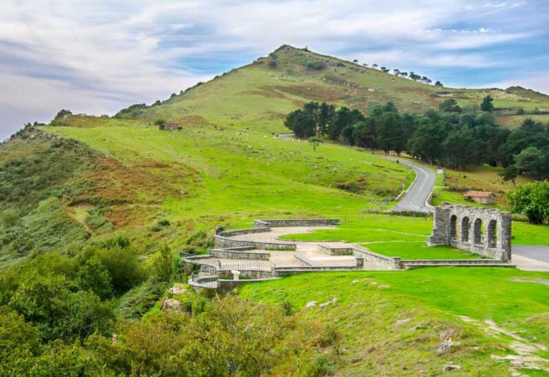 Chapelle en pierre à arcades et un belvédère sur les versants verts du mont, étape d'Irún à Saint-Sébastien du Chemin du Nord