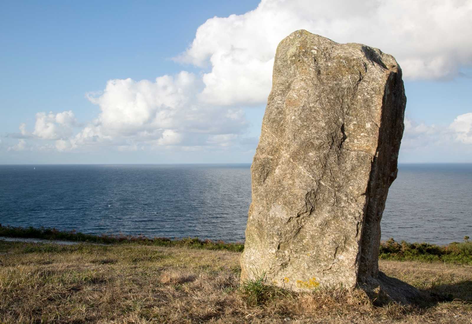 Menhir de piedra sobre el acantilado herboso frente al océano a la llegada a Malpica de Bergantiños en el Camino dos Faros