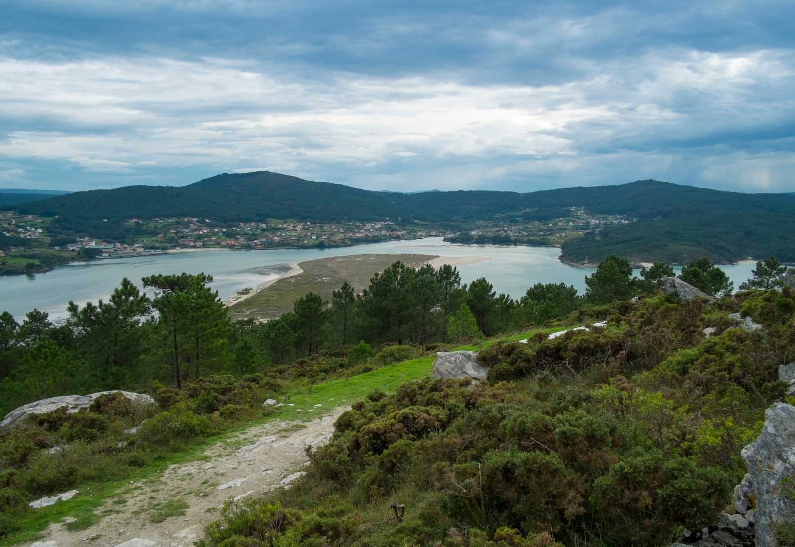 Vue sur la ria avec bancs de sable et collines depuis un sentier de lande sur l'étape de Playa de Niñóns à Ponteceso du Camiño dos Faros