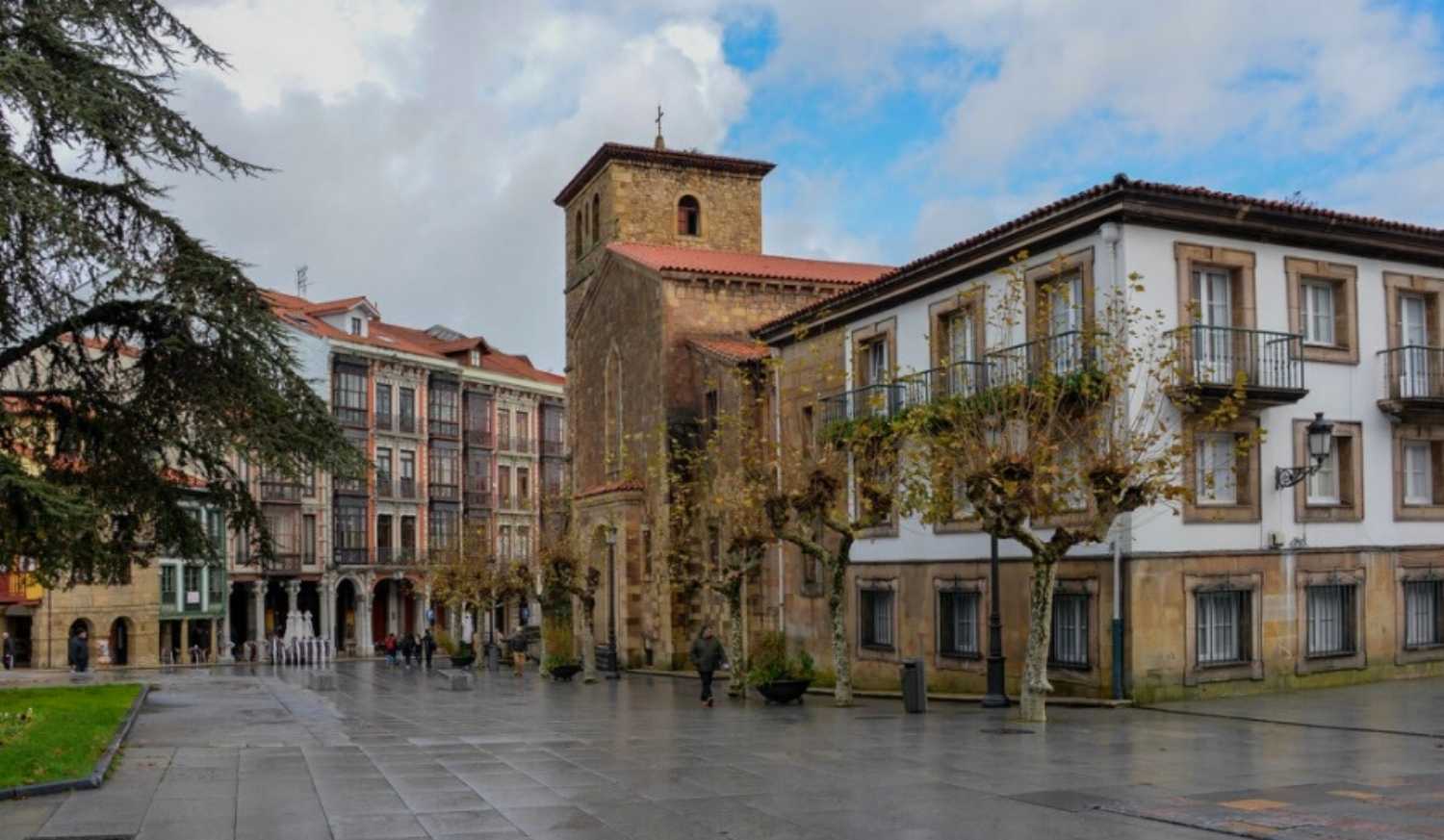 Place historique d'Avilés avec le clocher d'une église et des immeubles à galeries vitrées sur l'étape de Gijón à Avilés du Chemin du Nord.