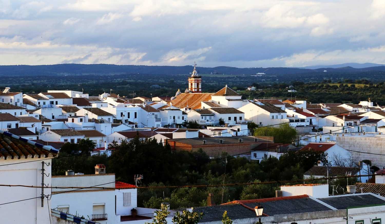 Panorama of Castilblanco de los Arroyos, a white town with its church tower and hills at dusk, Vía de la Plata.