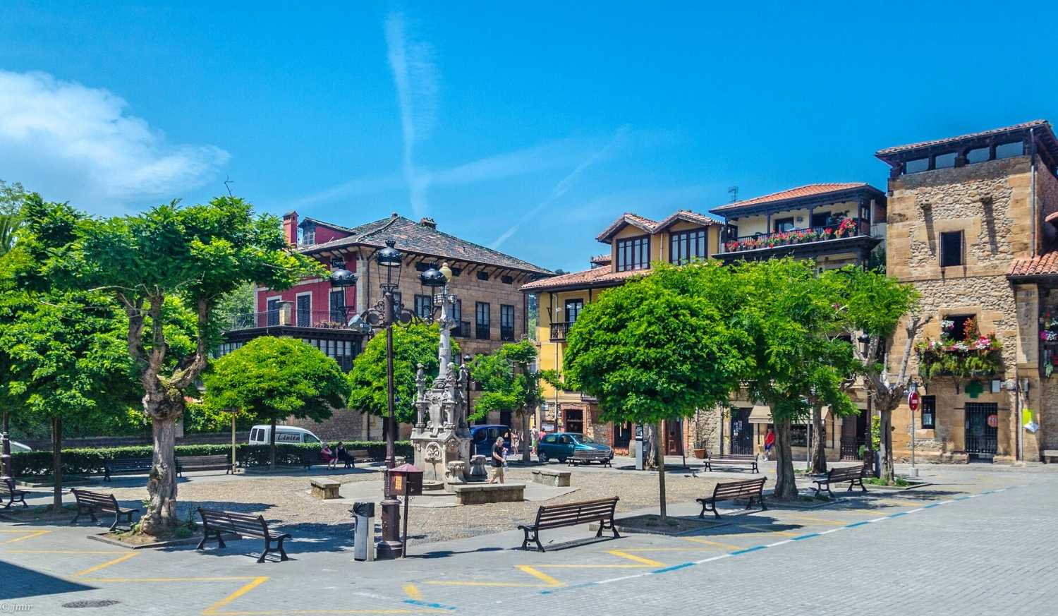 Place pavée avec fontaine en pierre et maisons traditionnelles lors de l'étape de Comillas à Colombres du Camino del Norte