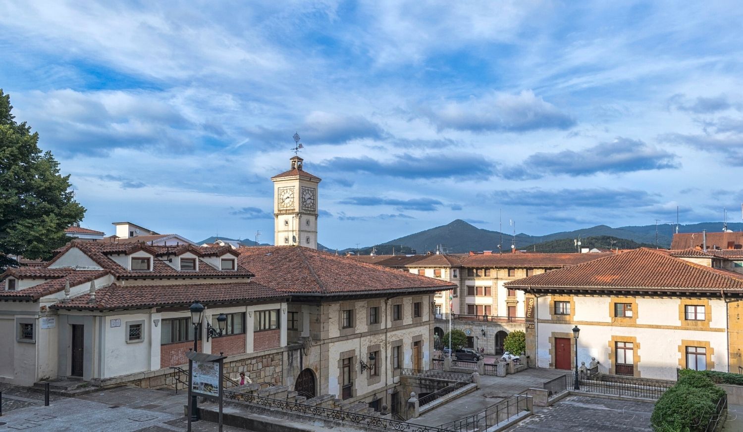 Toits rouges et une tour de l'horloge à Gernika-Lumo sous un ciel bleu avec montagnes sur l'étape de Gernika-Lumo à Lezama du Chemin du Nord.
