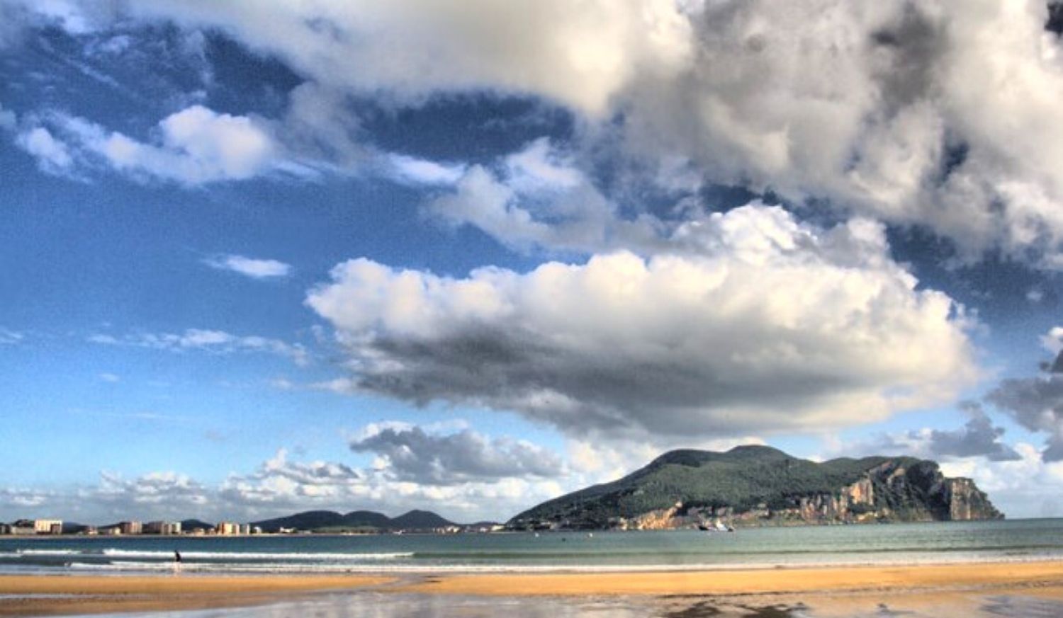 Spiaggia di Laredo sotto grandi nuvole con il monte che chiude la baia sullo sfondo, nella tappa del Cammino del Nord da Castro Urdiales.