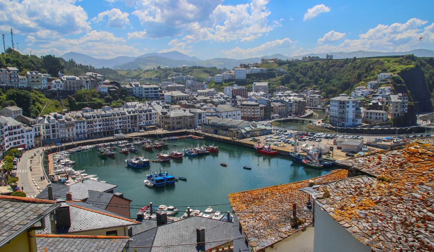 Vista panorâmica do porto piscatório de Luarca com barcos e casas brancas de telhado de ardósia na etapa de Luarca a La Caridad do Caminho do Norte.
