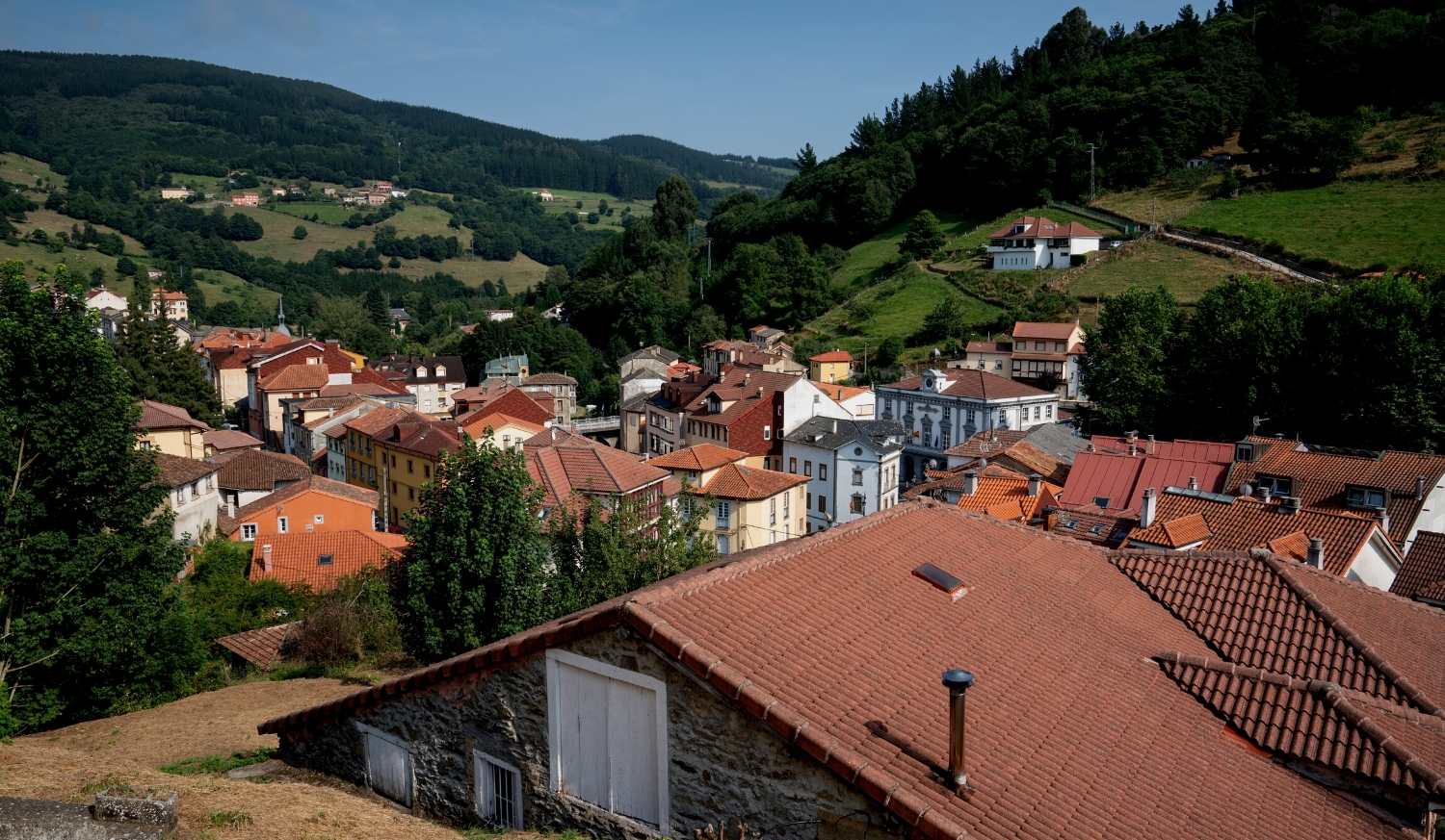 Pola de Allande com os seus telhados vermelhos num vale verde, início da etapa de Pola de Allande a La Mesa do Caminho Primitivo