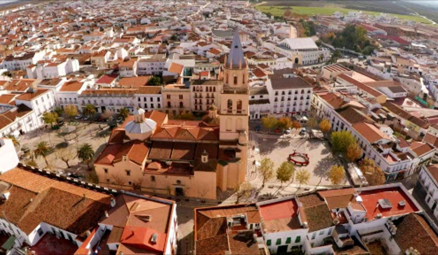 Vista aérea del pueblo con su gran iglesia de aguja entre tejados rojos en la etapa De Zafra a Villafranca de los Barros.