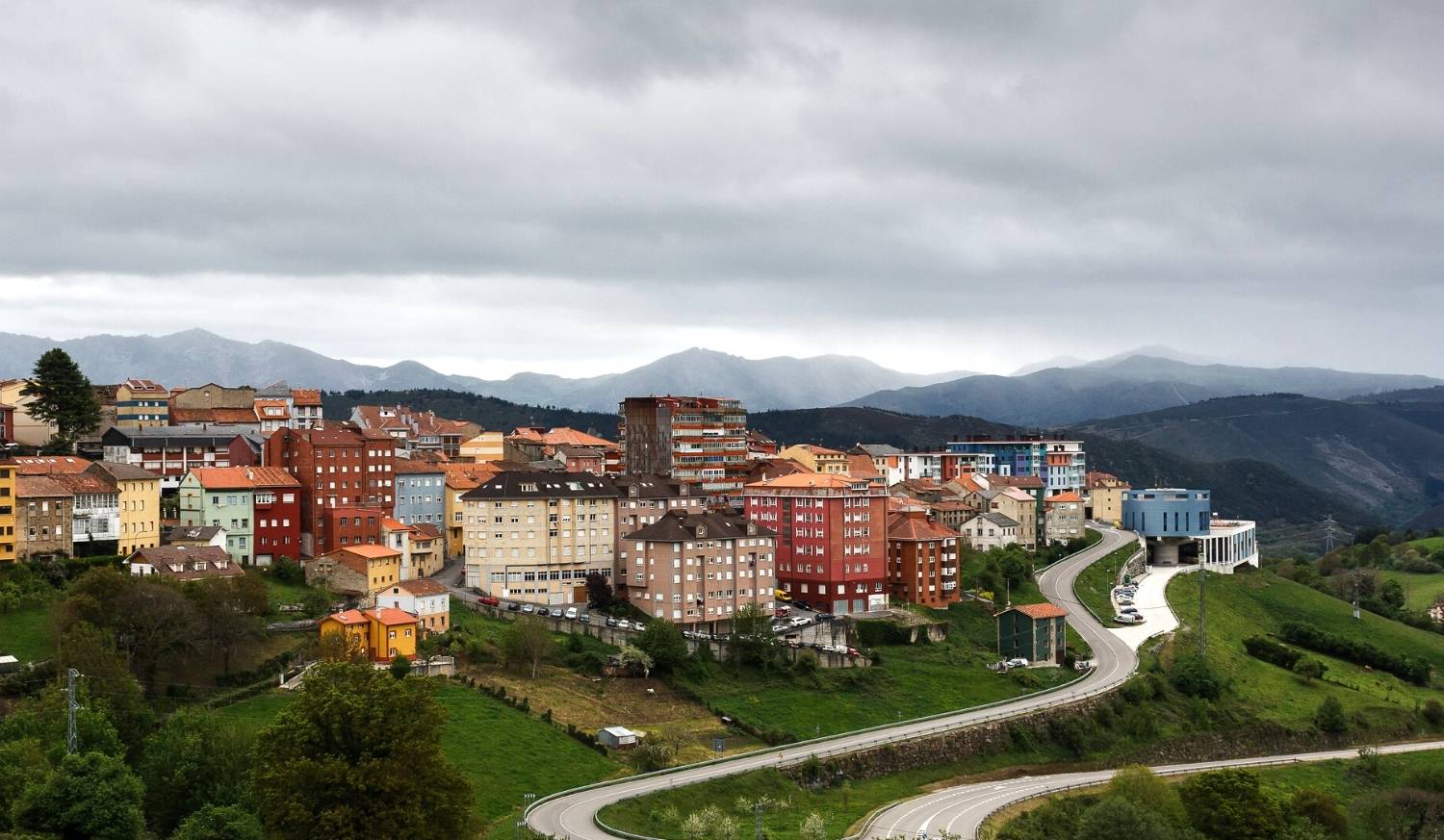 A vila de Tineo na encosta com edifícios coloridos e montanhas na etapa de Salas a Tineo do Caminho Primitivo