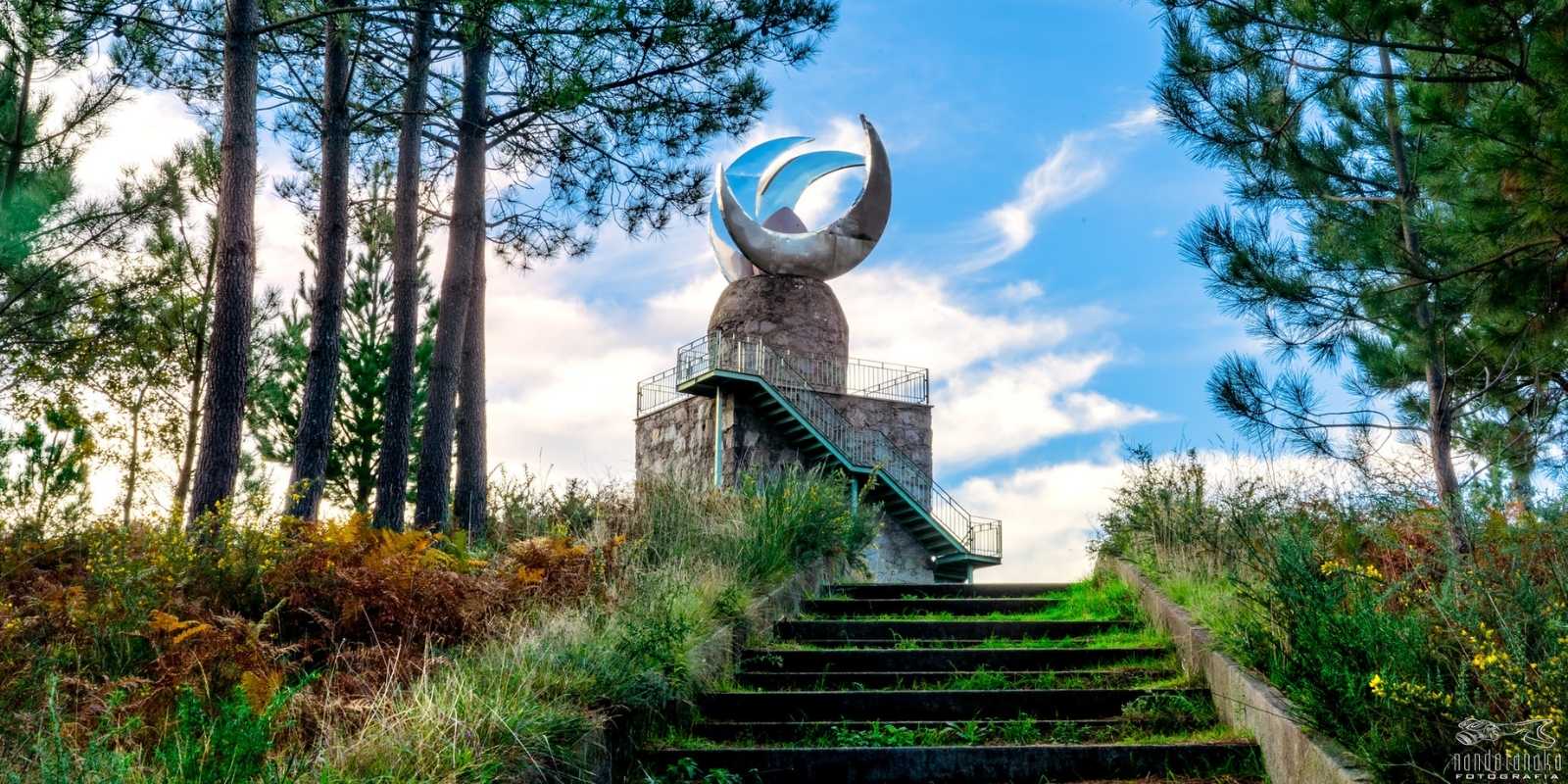 Escultura metálica moderna num miradouro de pedra entre pinheiros na etapa de A Illa de Arousa a Vilanova de Arousa da rota do Padre Sarmiento